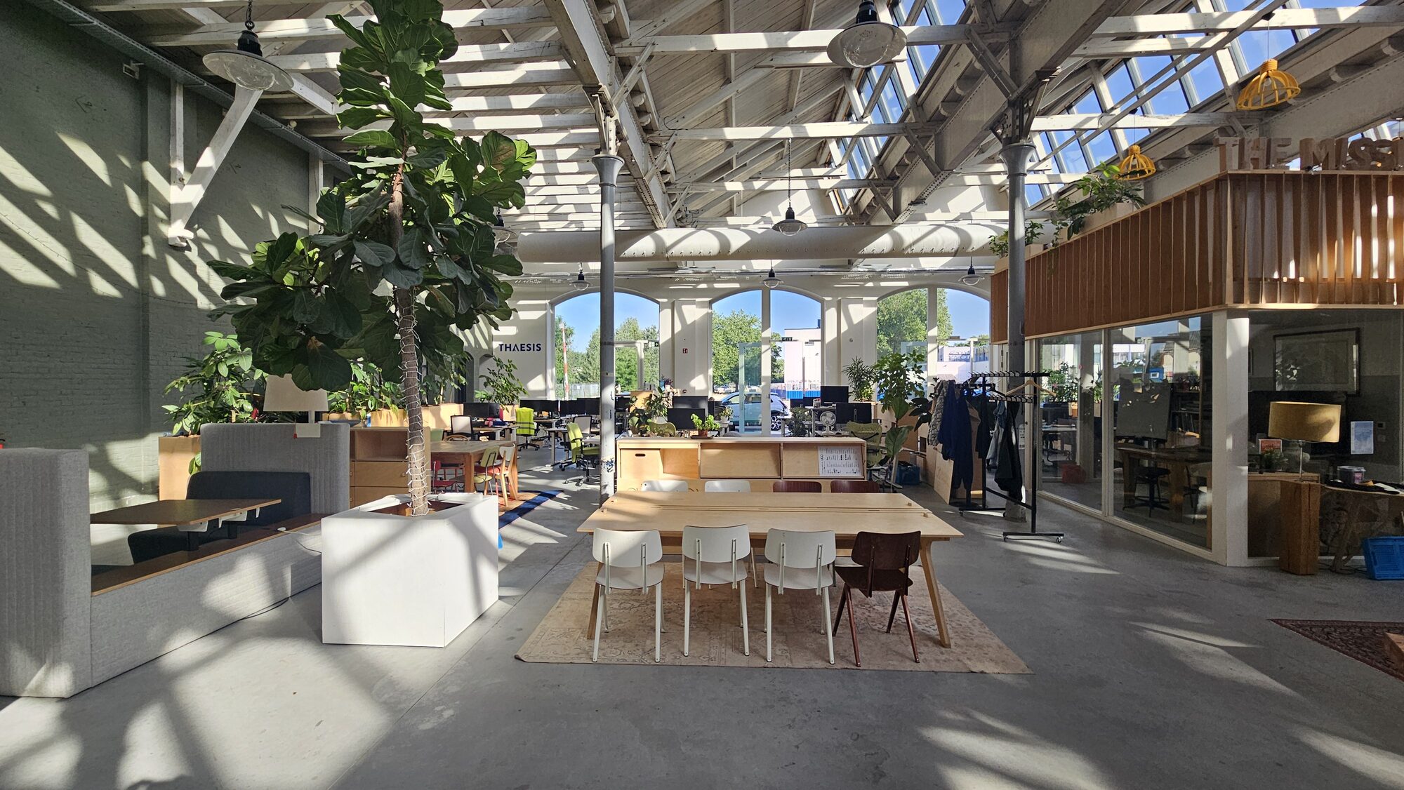 De centrale hal met een houten vergadertafel en de mezzanine op de achtergrond